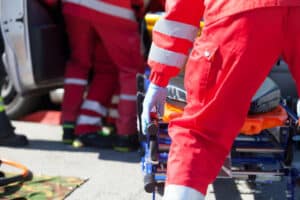 foto ravvicinata di un operatore sanitario che tira su una barella verso l'ambulanza